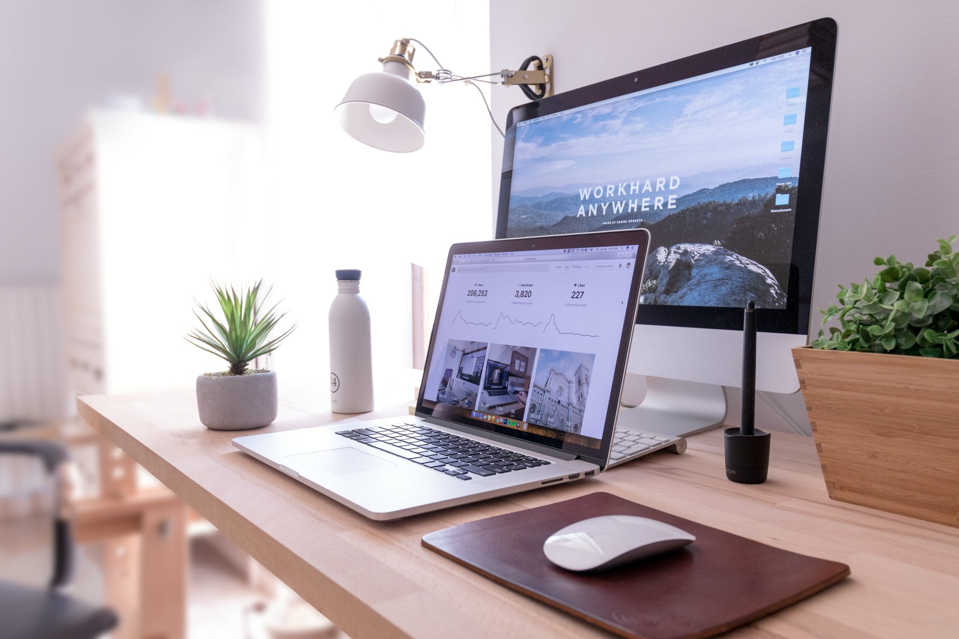 MacBook Pro sobre una mesa junto a un iMac blanco y un Magic Mouse.